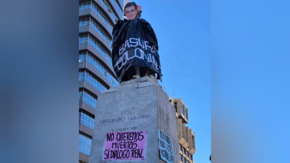 MUJERES CREANDO COLOCA IMAGEN DE RODRIGO PAZ SOBRE ESTATUA DE CRISTÓBAL COLÓN